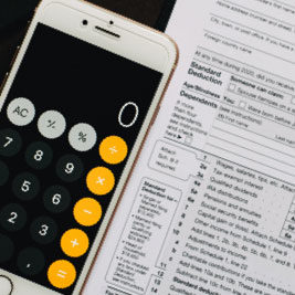 mac phone with calculator open next to tax forms