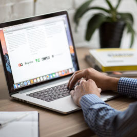 man typing on a mac laptop