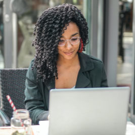 women outside sitting infront of laptop